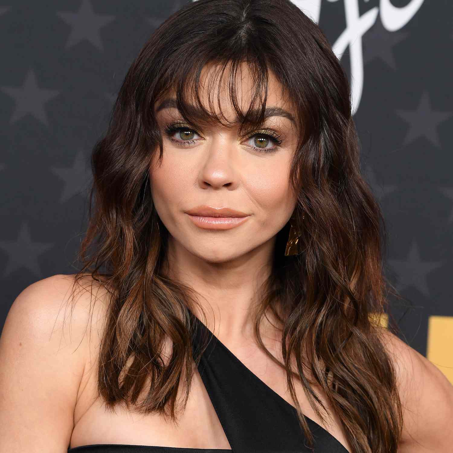 Sarah Hyland wears a wavy hairstyle with wispy bangs and face-framing layers