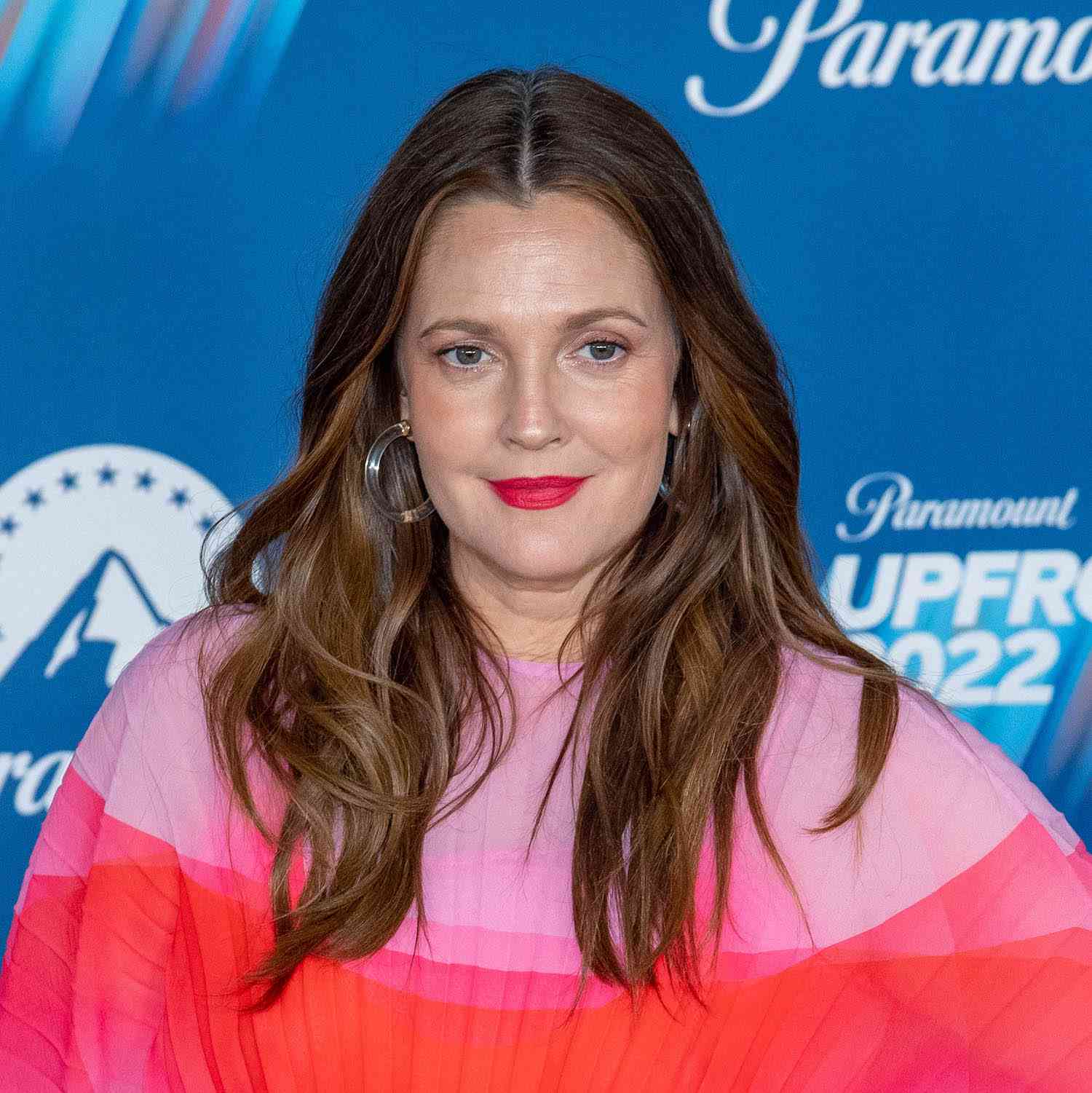 Drew Barrymore wears an undone, tousled wavy. hairstyle with face-framing layers