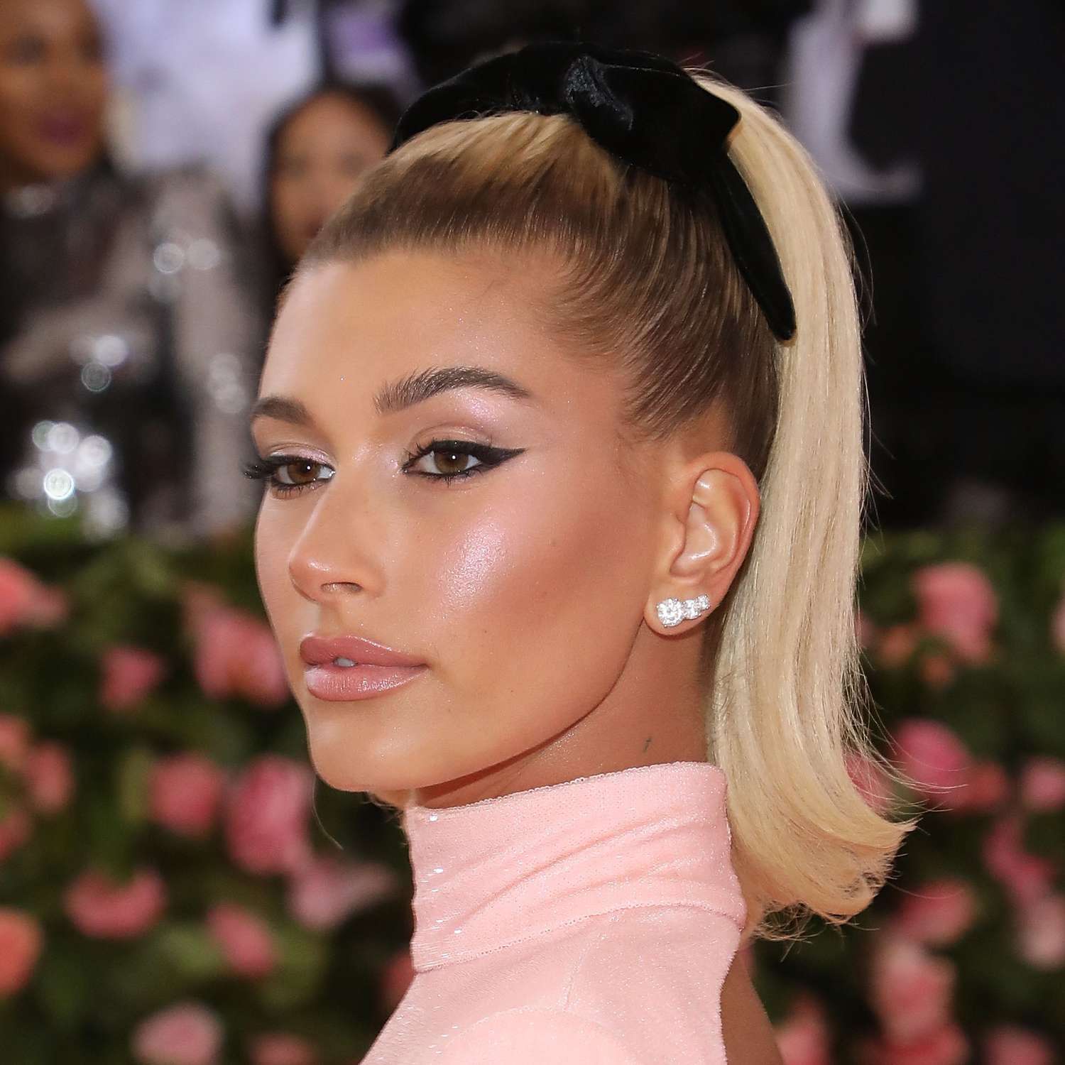 Hailey Bieber wears a ponytail hairstyle with flipped ends and black bow to the Met Gala