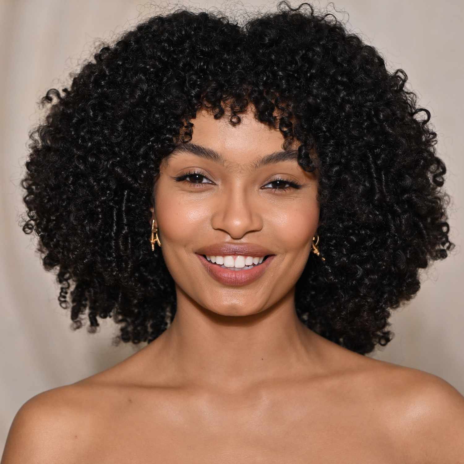 Yara Shahidi wears a heart-shaped afro hairstyle with bangs and face-framing layers
