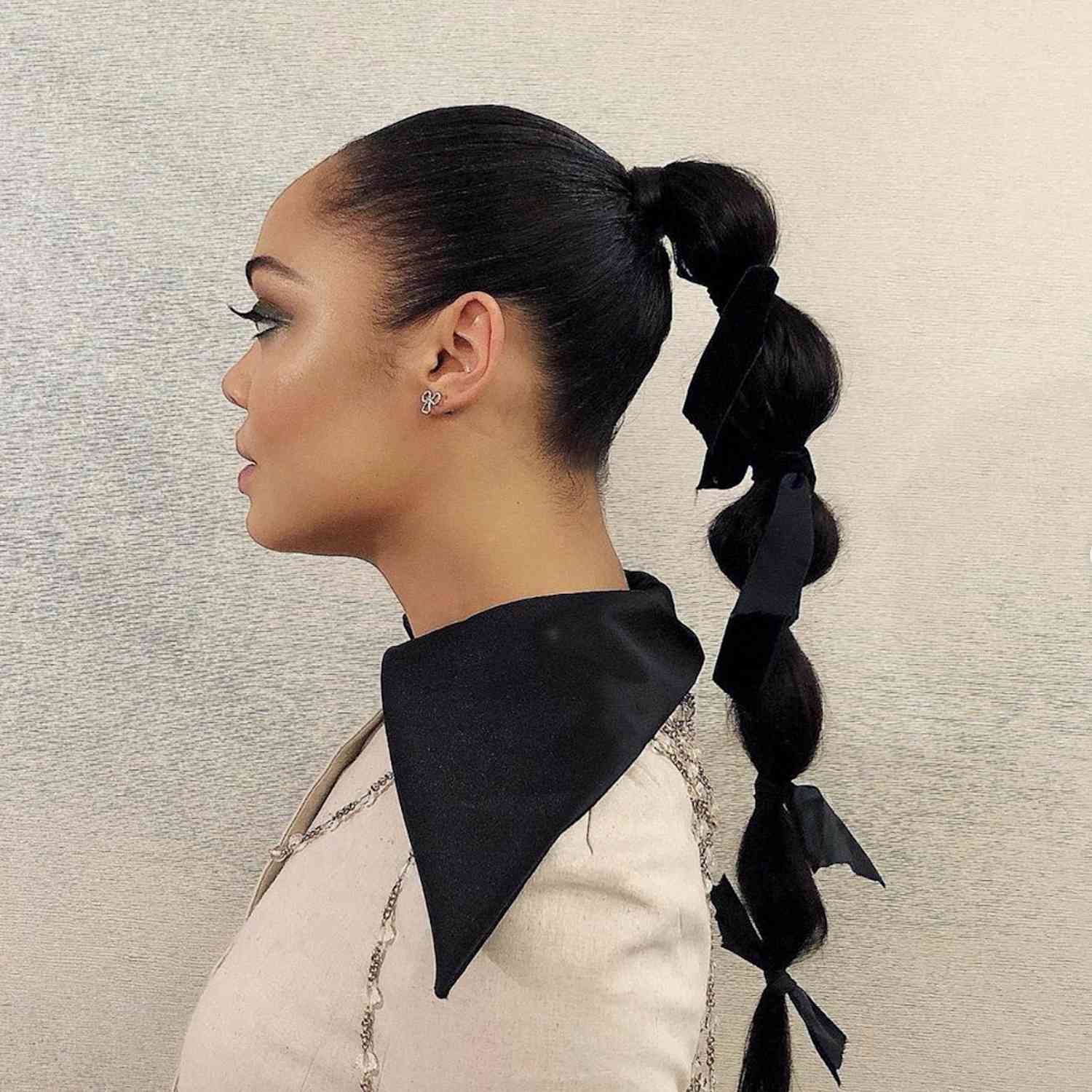 Side view of Tessa Thompson with a bubble ponytail with ribbon accents