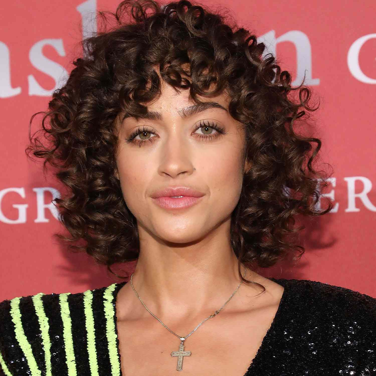 Alanna Arrington wears a short, curly hairstyle with bangs and face-framing layers