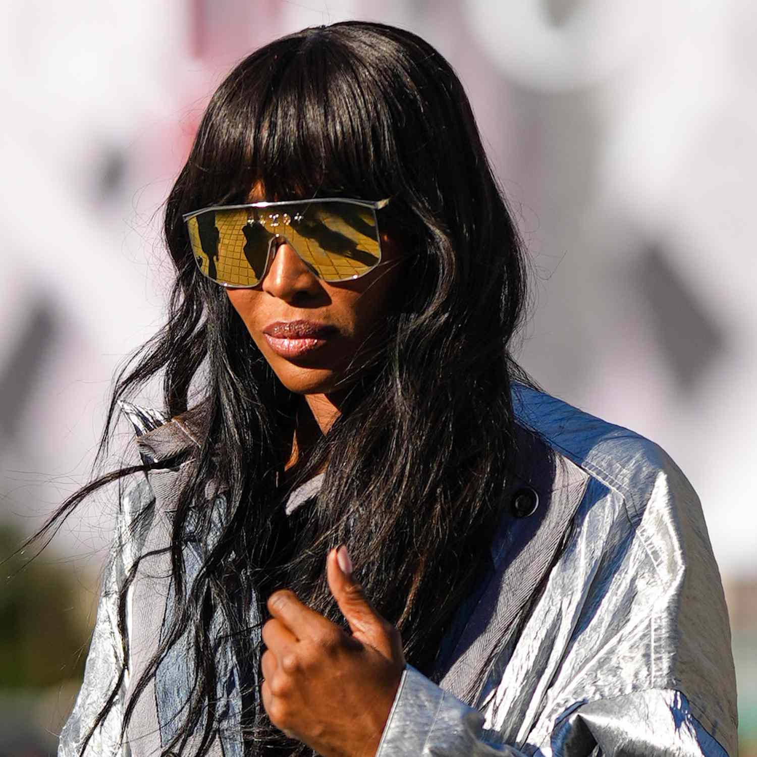 Naomi Campbell wears a tousled wavy hairstyle with bangs and aviator sunglasses