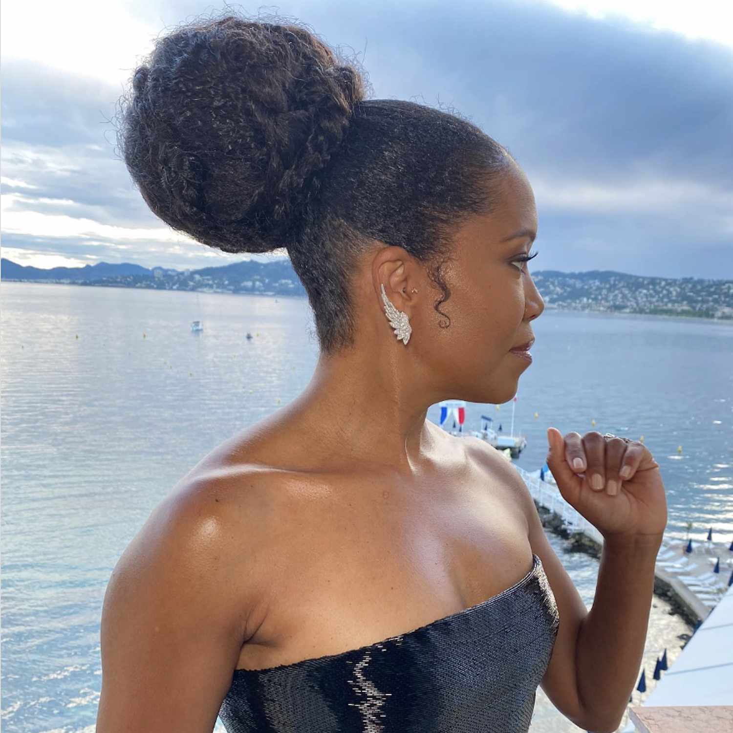 Regina King wearing a voluminous curly bun hairstyle with braided wrap and wing earrings