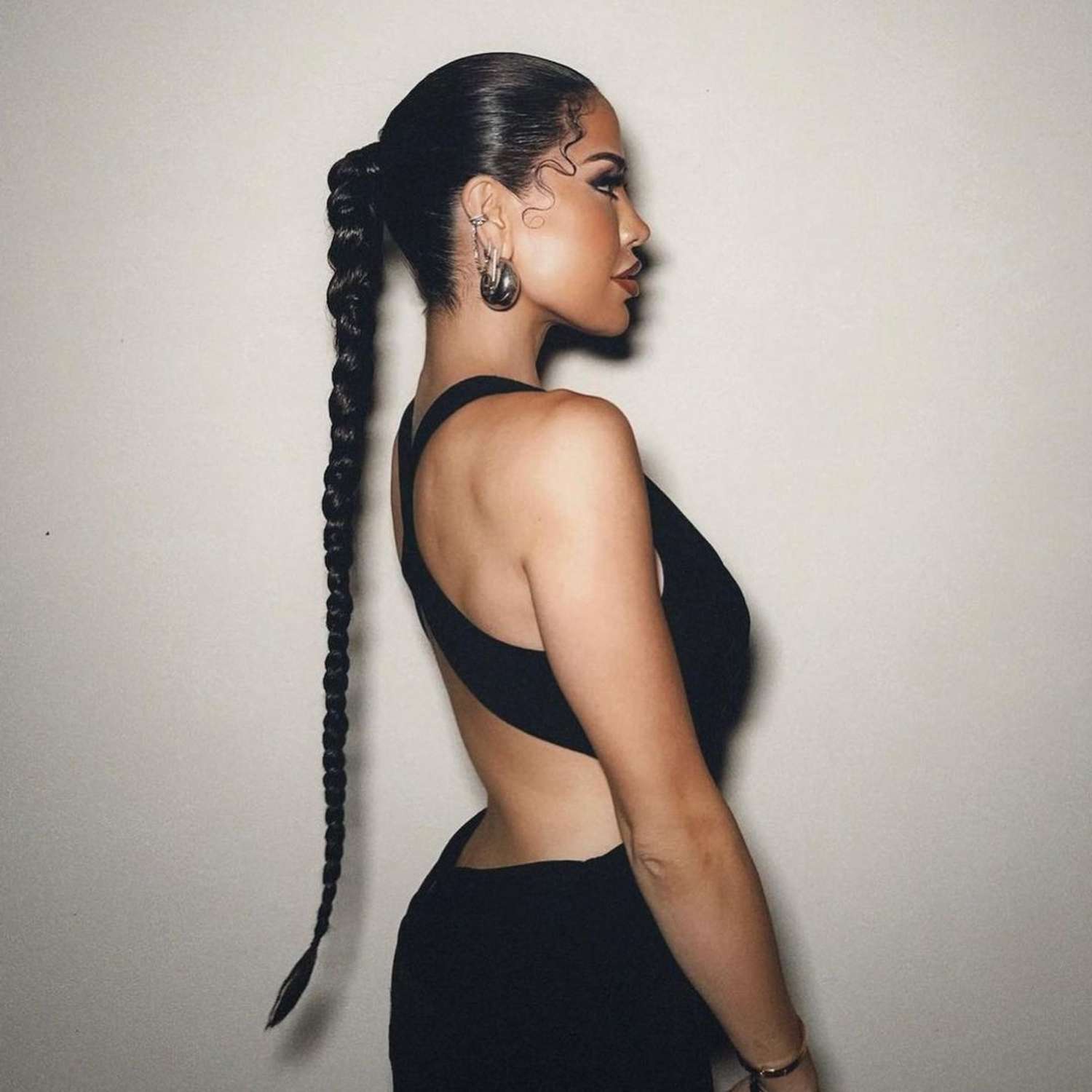 Side view of woman with ultra-long braided ponytail hairstyle with slicked roots and curly face-framing pieces