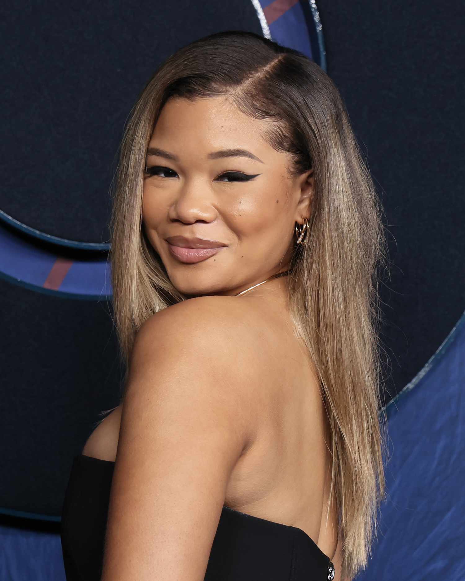 Storm Reid with a deep side part and long, straight hair