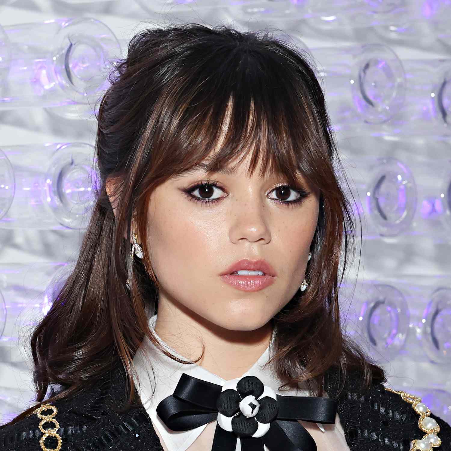 Jenna Ortega wears a shoulder-length half-up bob hairstyle with bangs and face-framing layers