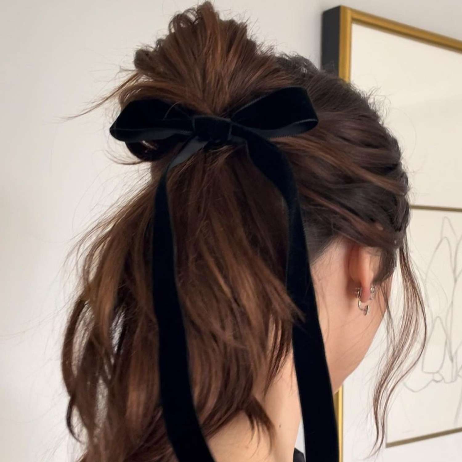 Back view of woman with messy half-bun ponytail hairstyle tied with black velvet ribbon