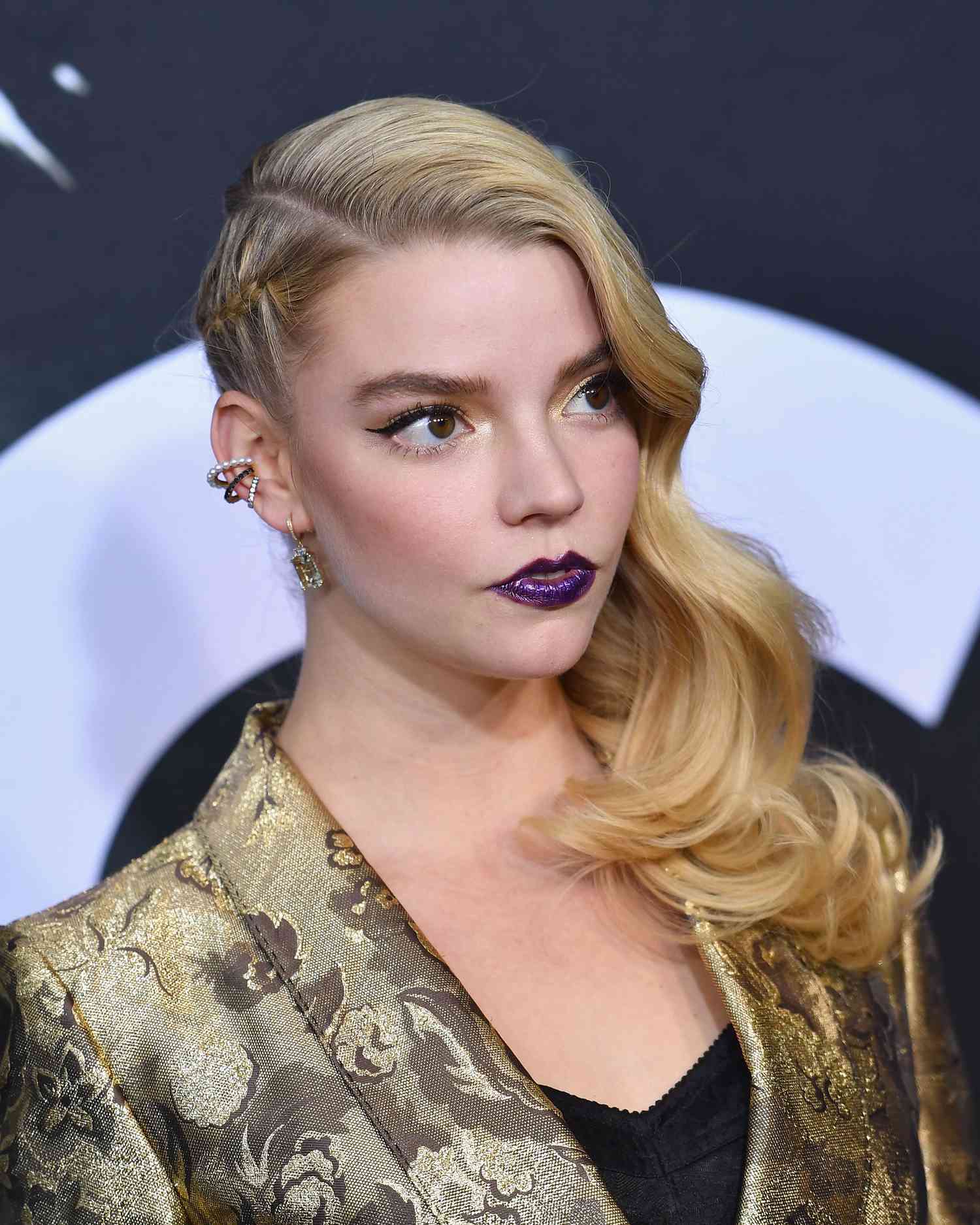 Anya Taylor-Joy with a deep side part, waves on one side of her head and a braid on the other