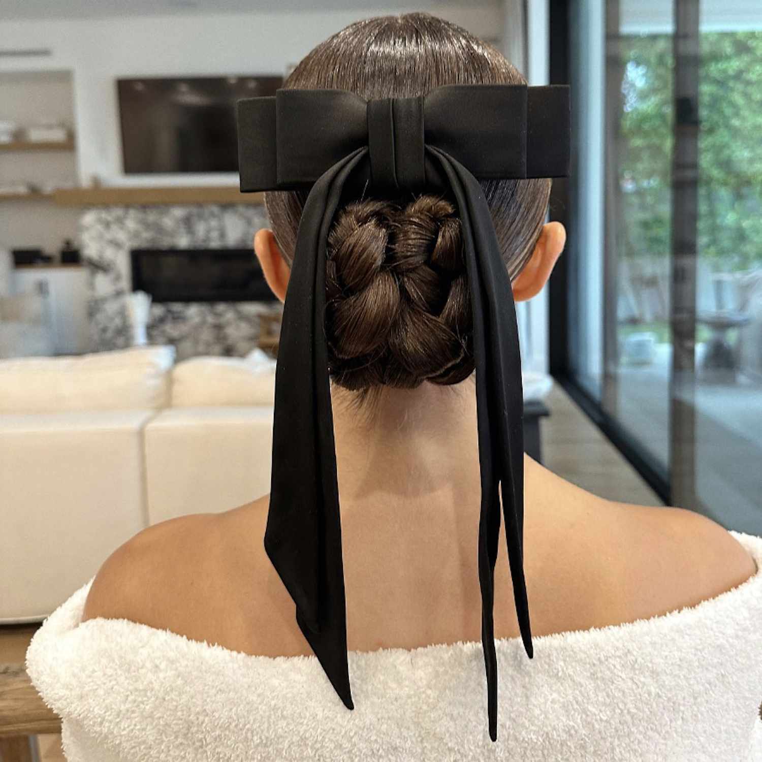 Back view of Olivia Culpo with a low braided bun hairstyle with bow