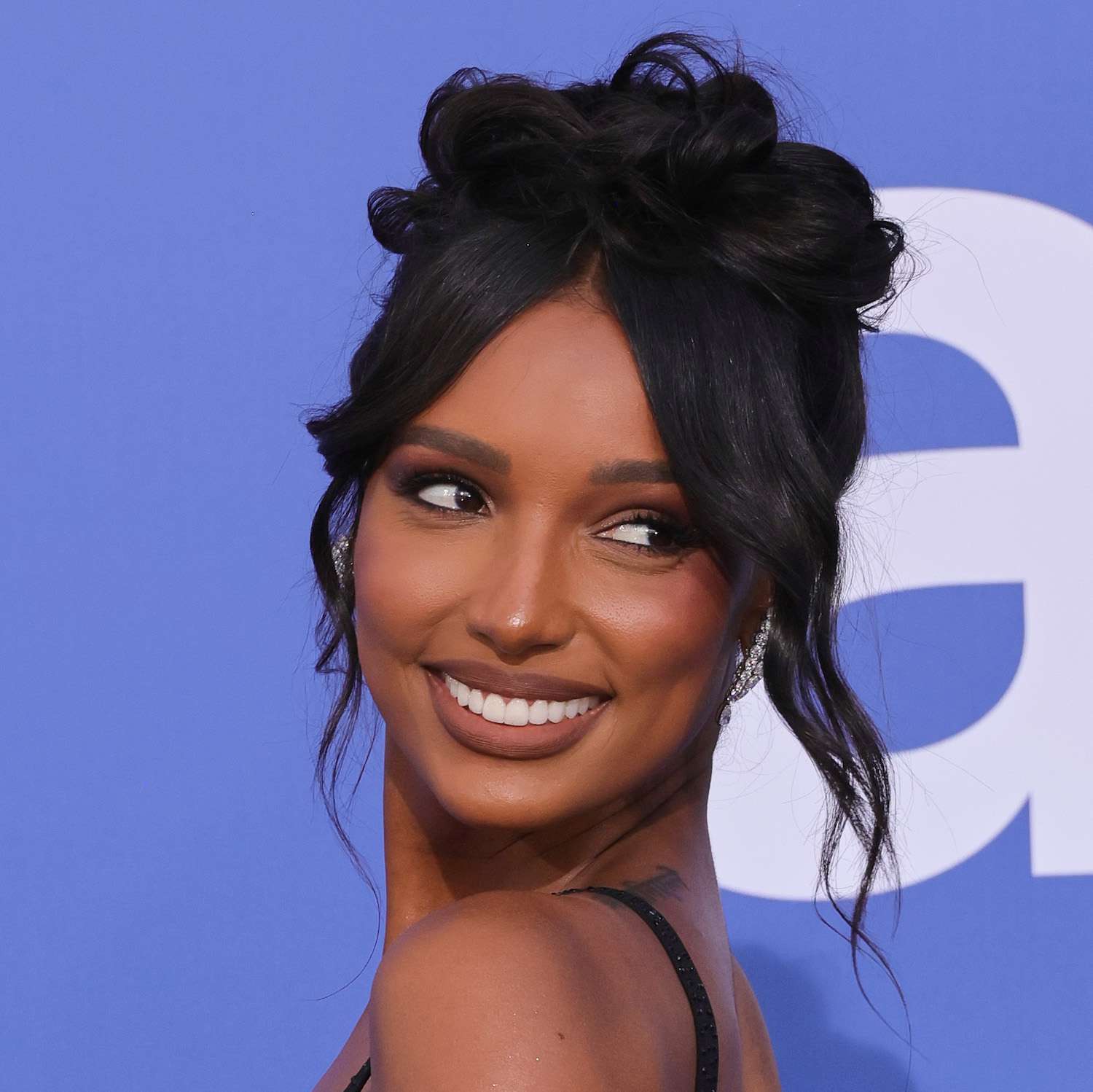 Jasmine Tookes wears an updo hairstyle with curled curtain bangs