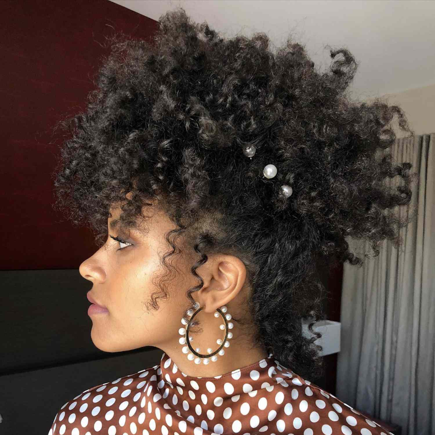 Zazie Beetz wears a curly updo hairstyle with pearl pins