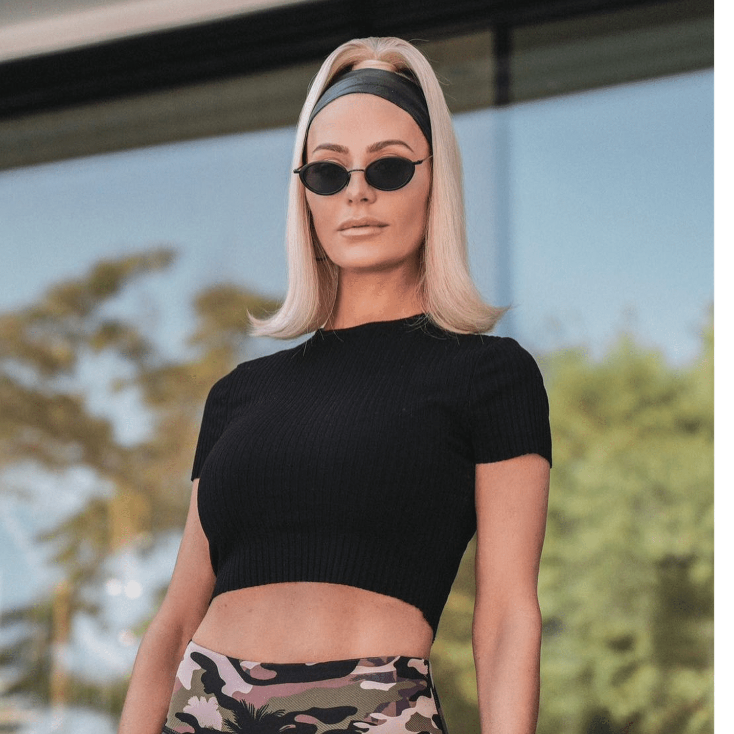 Dorit Kemsley wears a high ponytail hairstyle with flipped ends, headband, and oval sunglasses