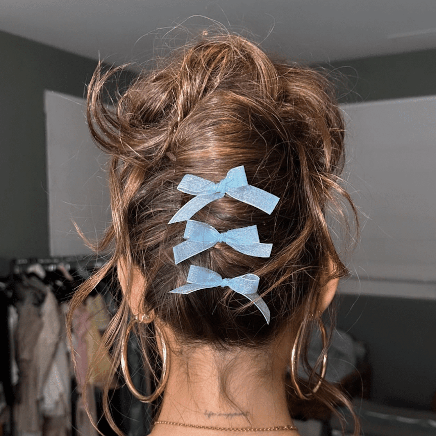 Madison Beer wears a messy french twist with three light blue bows along its spine