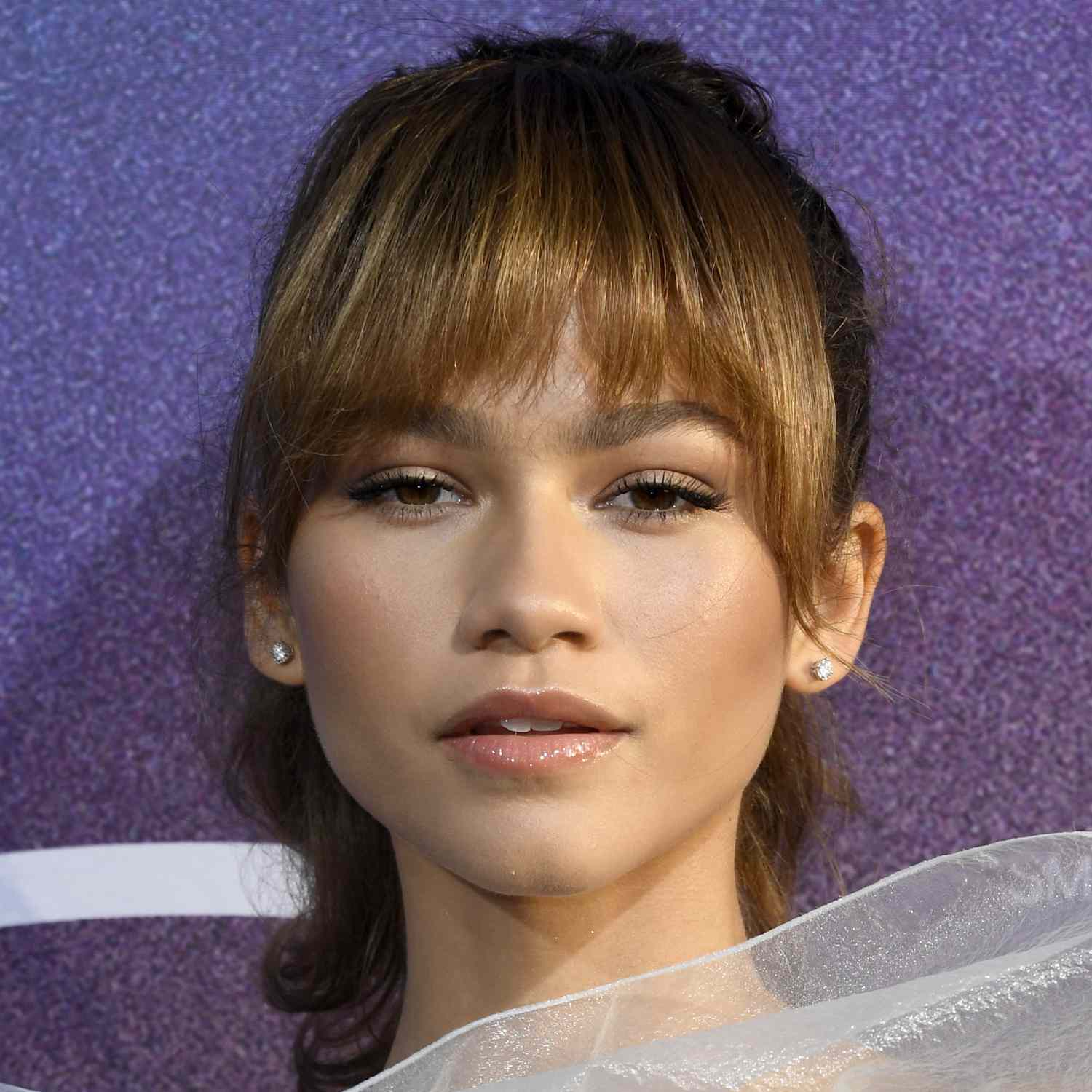 Zendaya wears french bangs against a mid-height ponytail at an LA premiere. 