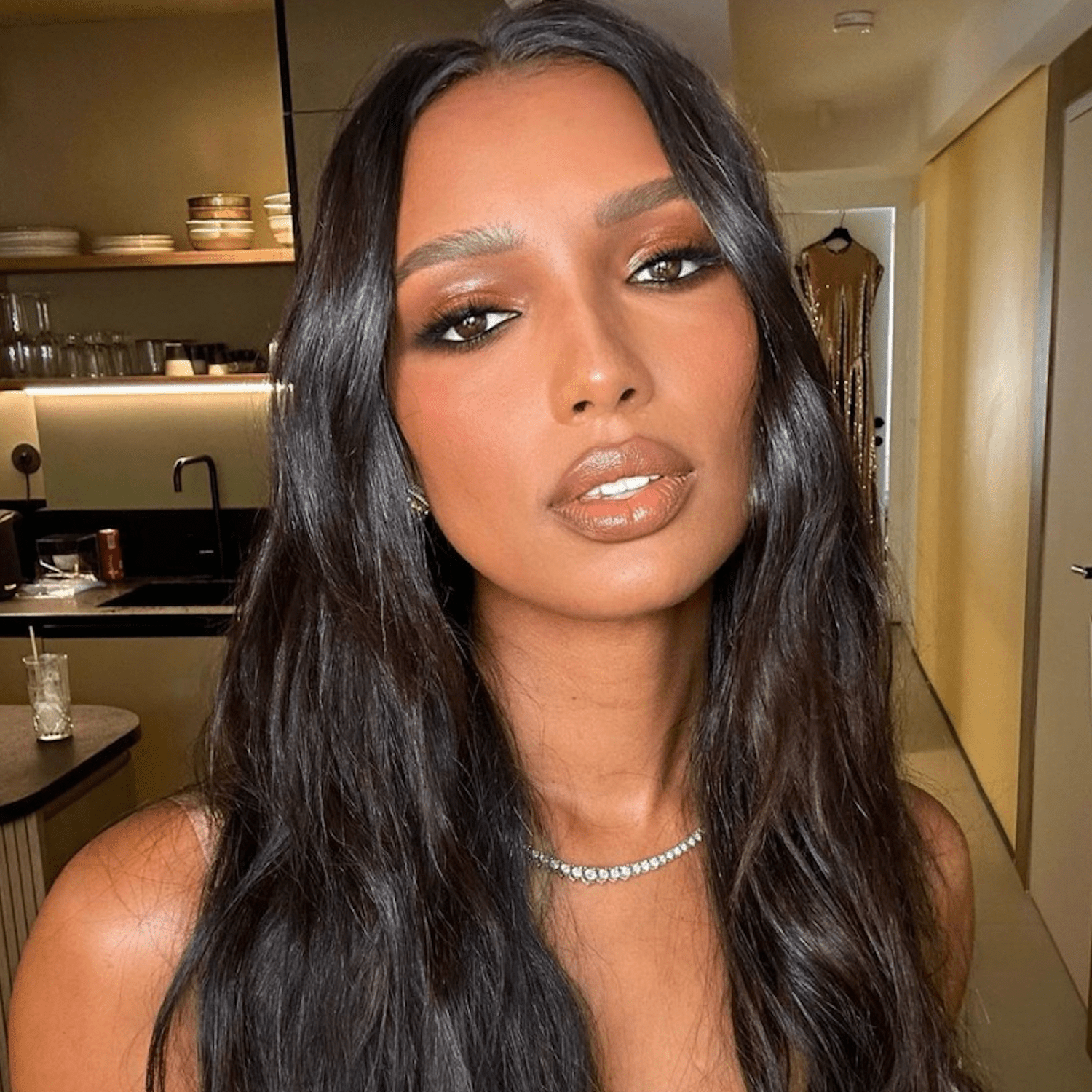 Jasmine Tookes wears her natural espresso brunette hair with matching extensions for length in a center parted wavy texture