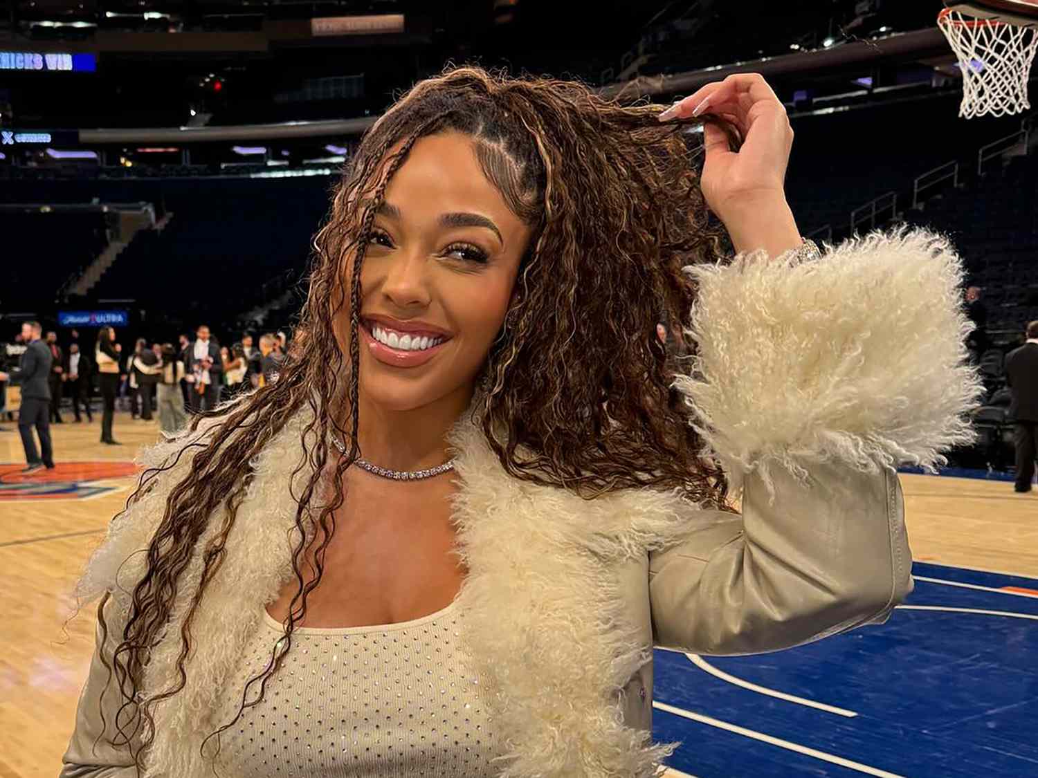 Jordyn Woods in front of the basketball court, holding her boho braids